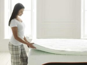 a woman lifting the edge of a mattress pad