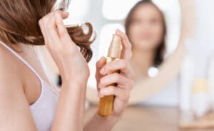 young woman sprays serum on tips