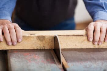 old man cutting a piece of wood