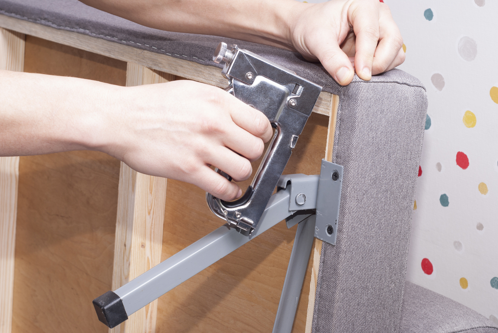Close up of hands stapling a new fabric in a furniture
