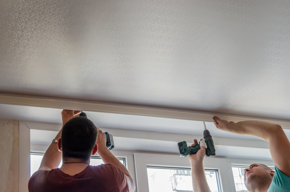 Men installing cornice for curtains on a stretch ceiling