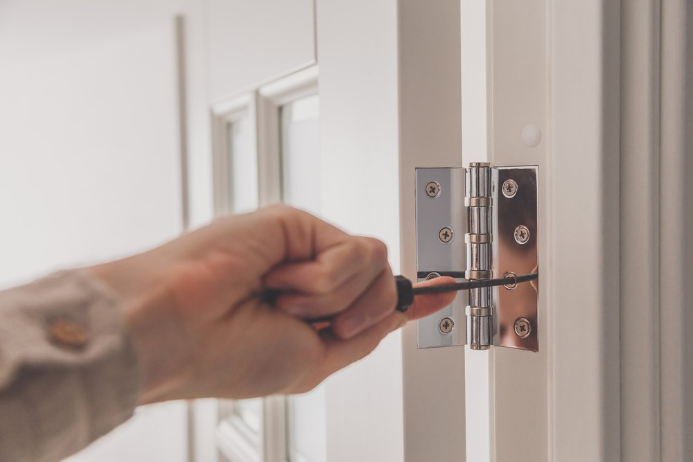 Man removing old hinges from the door